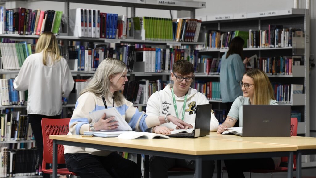 Students sat at a laptop in the library