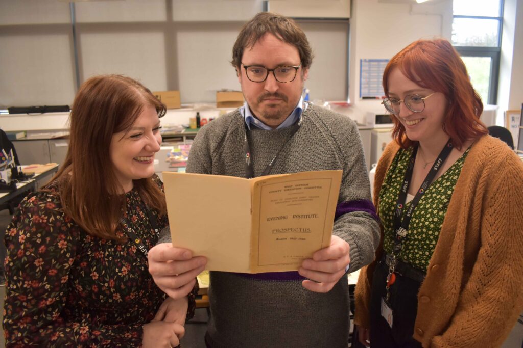 Cara Shirley, Daniel Connor and Siobhan Falconer looking at a prospectus dating back to the thirties.