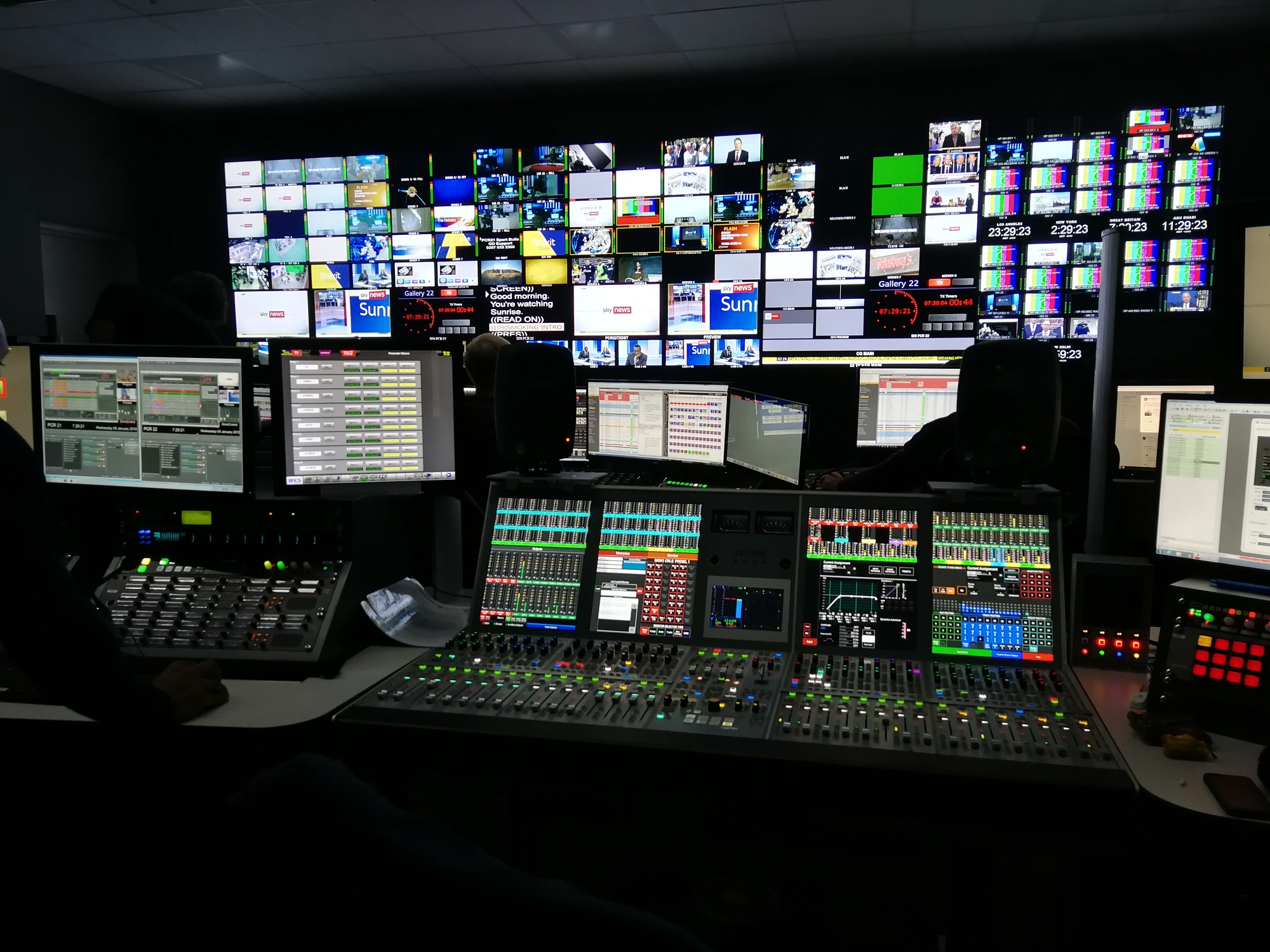 A series of screens behind-the-scenes in a television studio.