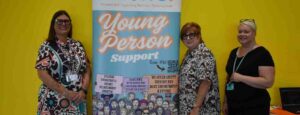 Three ladies standing by a banner saying 'Young person support'