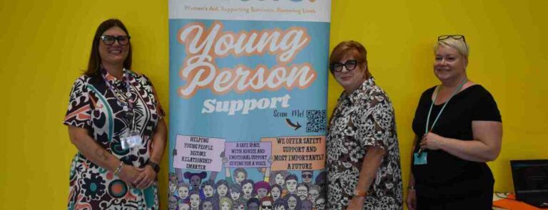 Three ladies standing by a banner saying 'Young person support'