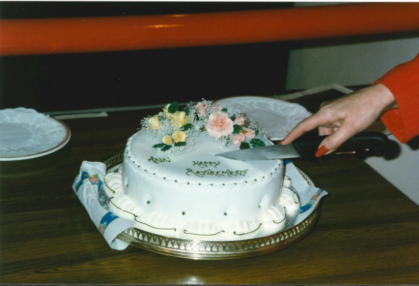 Ann Johnson cutting a cake with red nails.