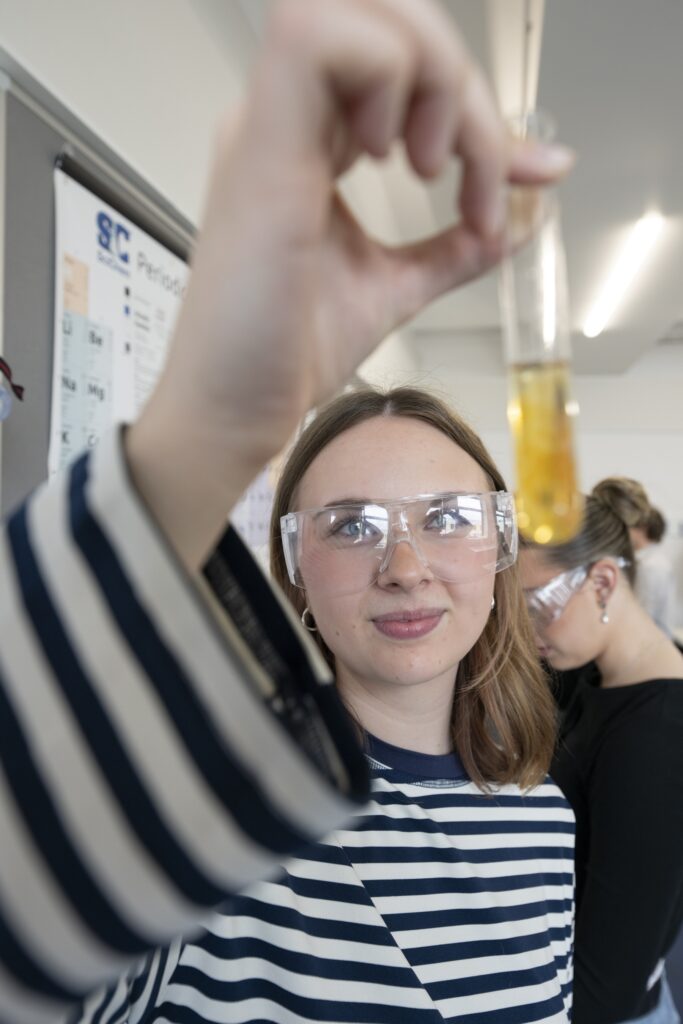 Advice and Guidance 10 Science student holding science equipment