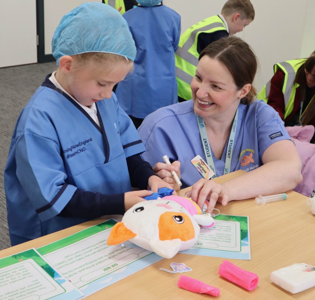 Young Students visit Haverhill for career event for kids - Skills Escalator Day 4 Paediatric recovery nurse Charlene Carol Newman practising bandaging with a student from Coupals Primary Academy